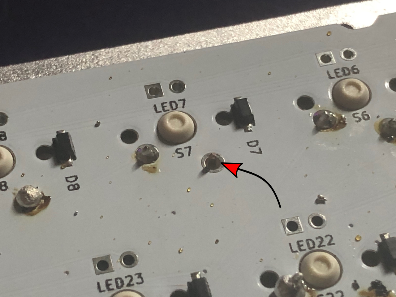 Back of PCB with an arrow pointing to an un-soldered pin next to the label S7