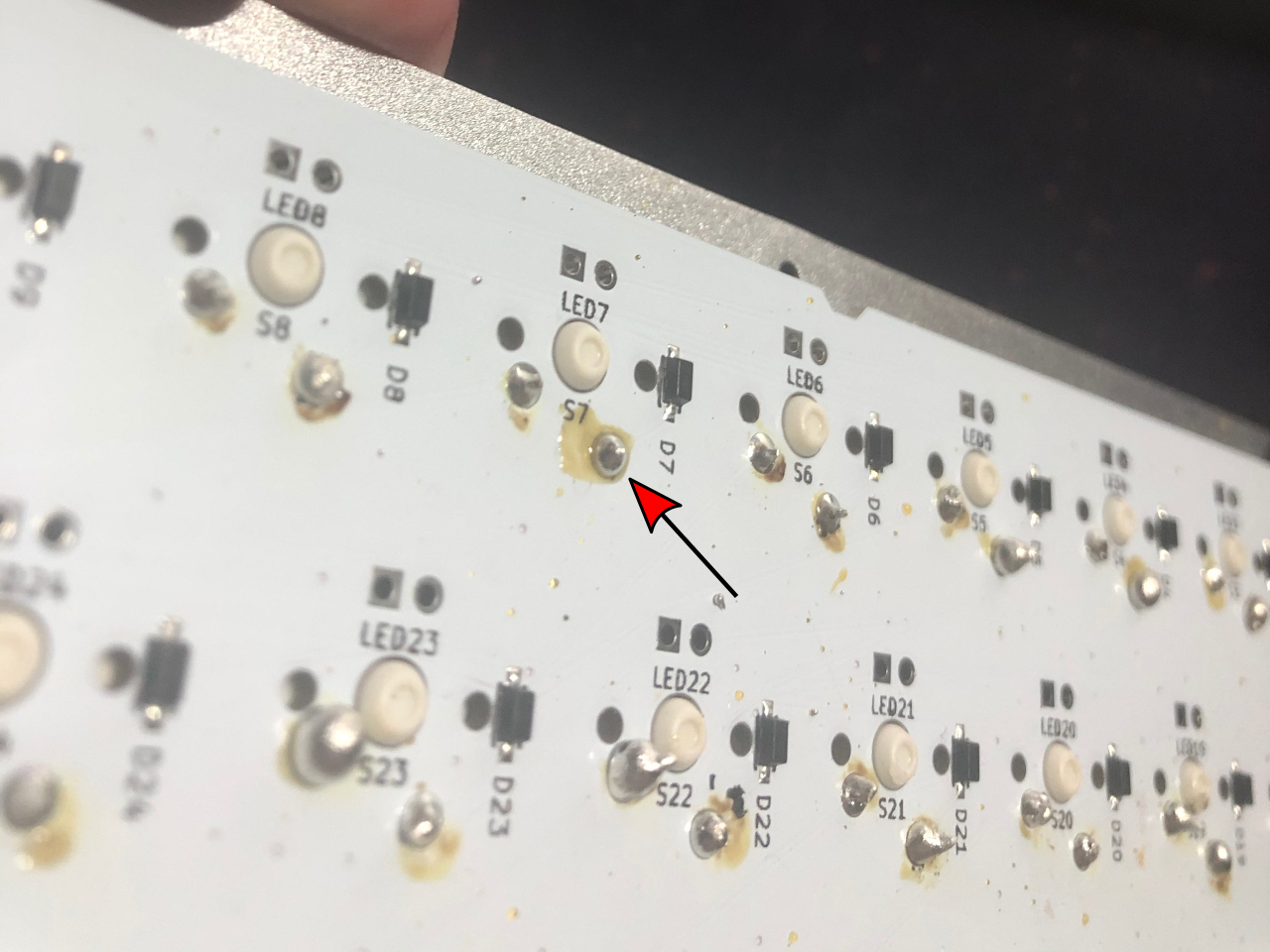 Back of PCB with an arrow pointing to a newly-soldered pin next to the label S7